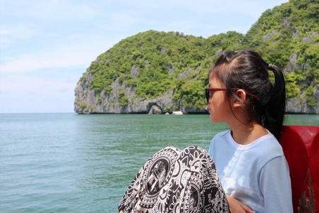 亚洲女孩坐在一艘与该群岛的自然观