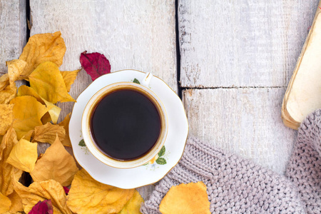 秋天，秋天的树叶，热蒸杯咖啡和木桌背景上温暖的围巾