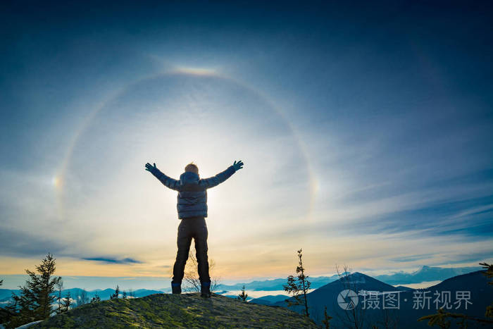 徒步旅行的男孩站在山顶上举起双手