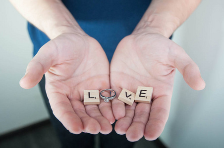 字母表字母木块瓷砖情人节爱的概念与结婚戒指在男子手中
