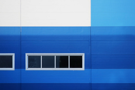 一幢大型办公楼的墙面是蓝色和白色的。有四个窗口