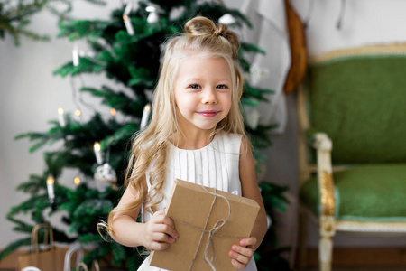 愉快的小微笑的女孩与圣诞节礼物箱子。圣诞快乐, 节日愉快