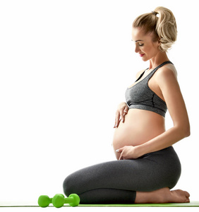怀孕的妇女做运动伸展练习绿色的重量。孕产妇期望健康生活与体重控制概念