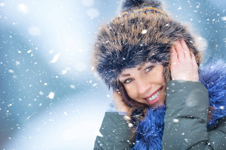 美丽微笑的年轻女子穿着暖和的衣服。冬季雪中画像的概念