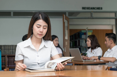 可爱的亚洲学生读书书在图书馆大学