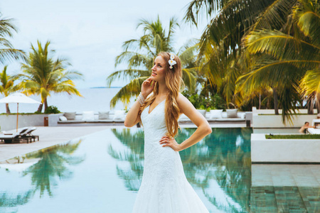美丽的新娘站在游泳池在一个的婚纱礼服