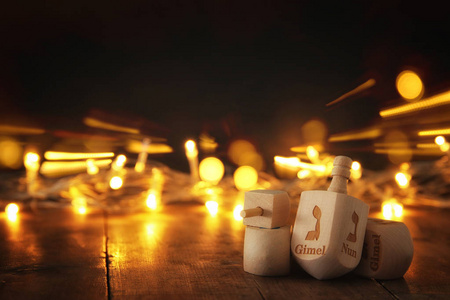 犹太节日光明节与木制陀螺集合 旋转的陀螺 和金黄色的灯光，在桌子上