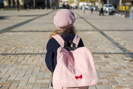 时髦的小女孩与背包, 在大衣和法国贝雷帽跑到学校