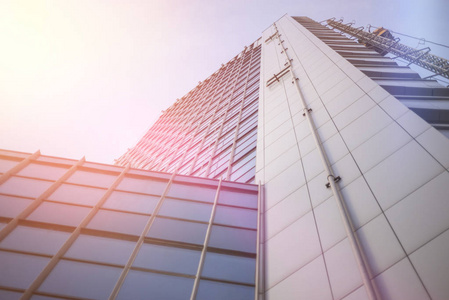 在商业区的现代摩天大楼的底部对蓝天, 太阳的眩光。办公楼