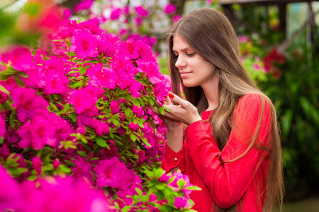 幸福的年轻妇女与非常长的头发在玫瑰园的红色上衣