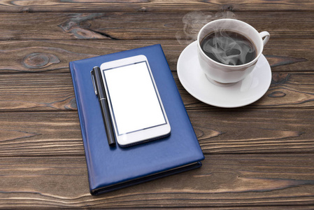 木制背景下的笔记本钢笔智能手机咖啡杯