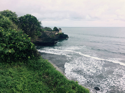巴厘岛海岸的岩石热带树木和海浪的景观