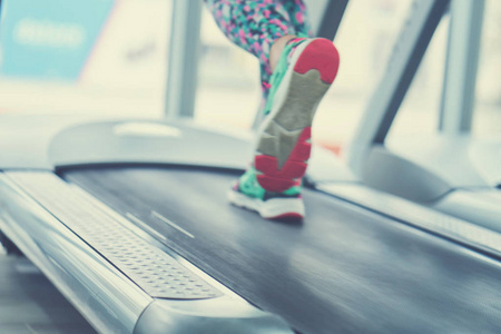 女性的肌肉脚的运动鞋在健身房的跑步机上