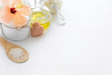 健康设置。海盐在玻璃, 肥皂, 毛巾, 橄榄油和花在白色纹理背景。复制空间。平躺