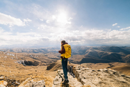 活跃的年轻女孩穿越高加索的山脉, 带着黄色的背包, 享受大自然
