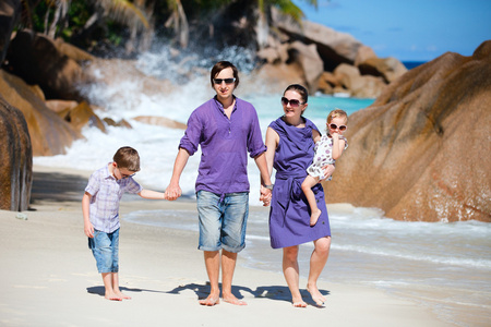 年轻的家庭在海滩上散步