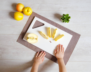 石材切割板, 苹果和儿童的手在一个轻背景。健康食品概念与复制空间。顶部视图