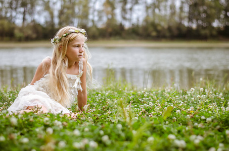 美丽的 sasd 白种女孩与长金色的头发在粉红色的礼服独自坐在河边的绿草仙女