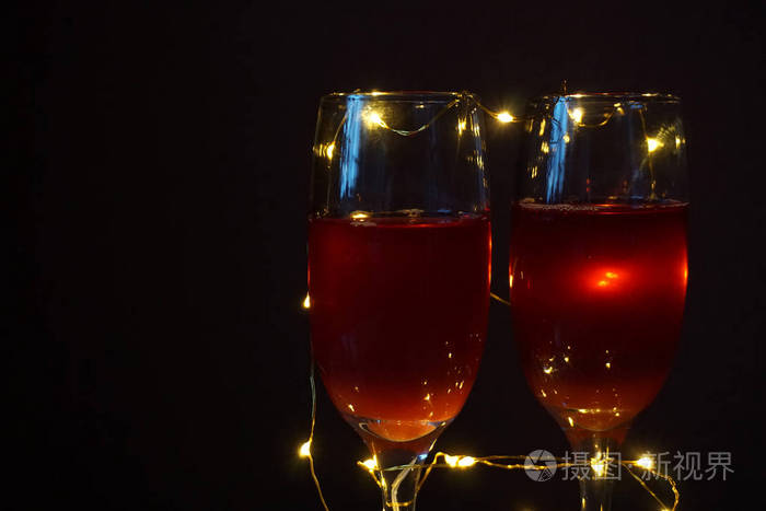 两杯玻璃杯.红酒.夜光花环.黑暗的背景.浪漫的设置.情人节的主题.