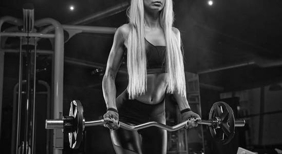 年轻美丽的女孩运动员健美在健身房做 exerci