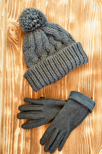 灰色的帽子和手套编织在一个木质的表面。这个概念是在秋或冬的日子里保持温暖