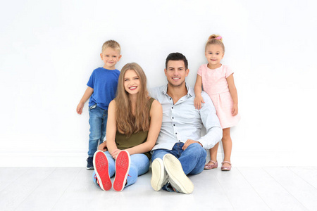 幸福的家庭坐在地板附近的白色墙壁在他们的新房子