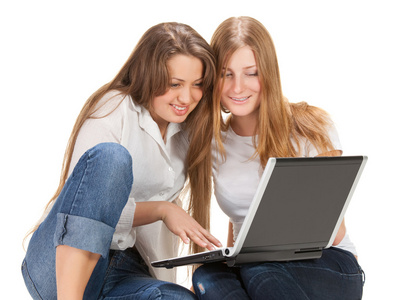 两个年轻快乐的学生女孩在笔记本电脑上工作