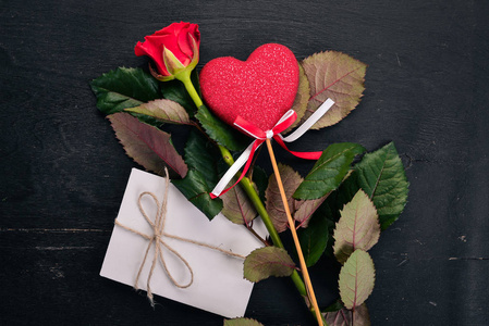 给心爱的人的信。一个信封, 一朵玫瑰, 一份礼物。在木制背景上。顶部视图。文本的可用空间