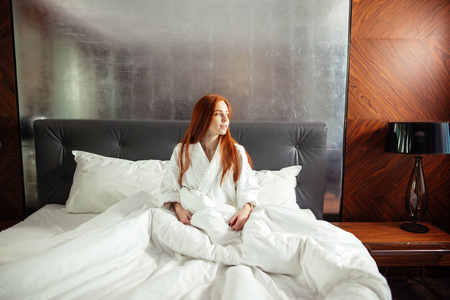 红头发的年轻女人坐在床上放松的雀斑