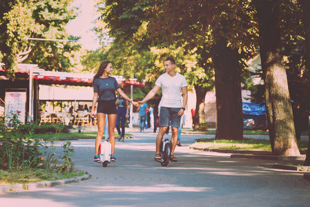 年轻的白种情侣骑电动踏板车横跨城市