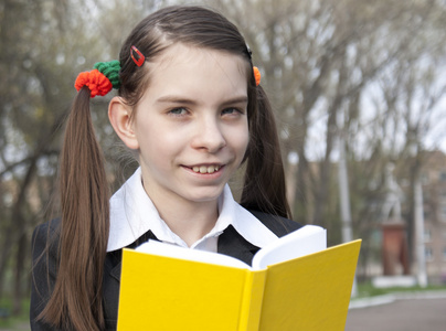 十几岁的女孩拿着一本书在一个公园