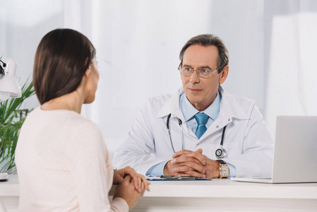 男性医生和女性病人坐在诊所谈话