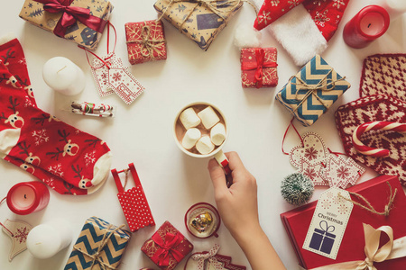 圣诞背景与手工礼品包裹在工艺纸和妇女的手与杯热巧克力