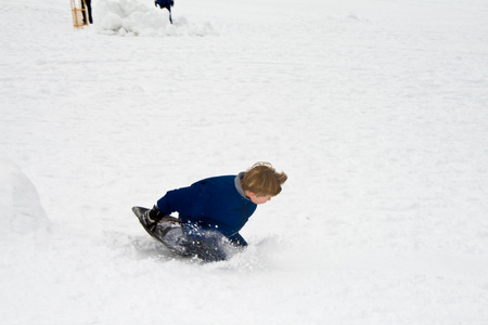 白雪皑皑的冬天，孩子正滑下山坡