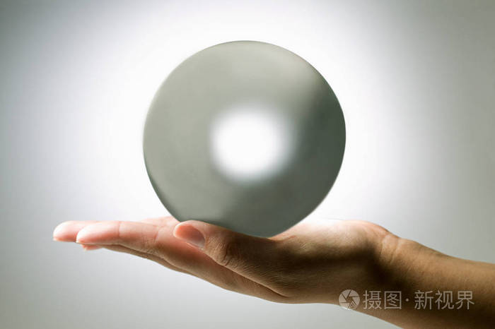 在白色背景下手持水晶球的人的裁剪镜头