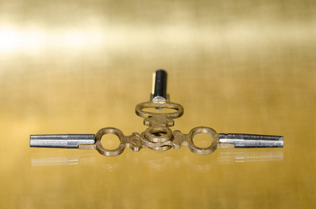 三古董黄铜口袋手表的钥匙铺设在金色的表面