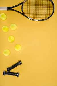 黑哑铃和网球拍与球孤立在黄色