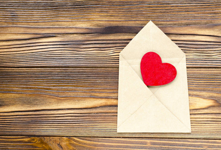 牛皮纸信封与木质表红色的心脏在木桌