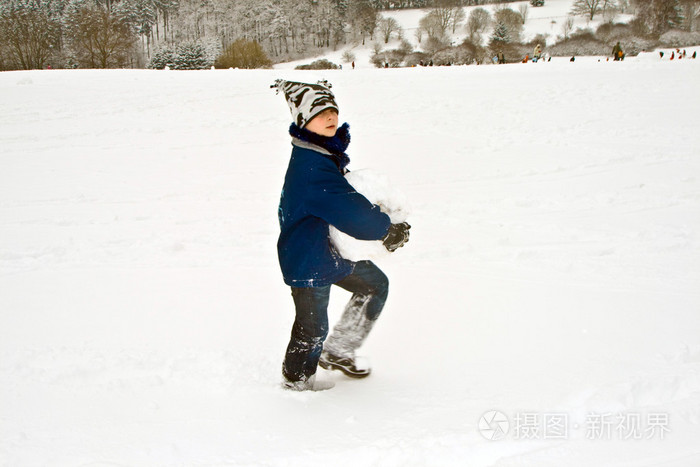 小孩手里拿着一个大雪球给雪人