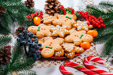 圣诞姜饼饼干自制的红盘子与树枝的圣诞树和装饰在家里的新年表。圣诞快乐明信片