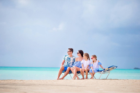 年轻家庭度假在日光浴在白色海滩