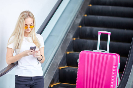一个女孩坐在手机上的粉红色的手提箱的背景