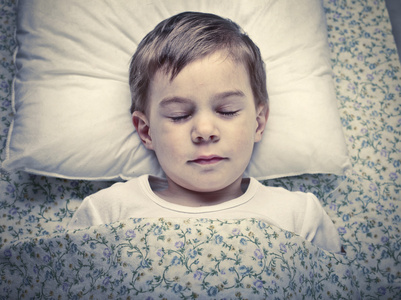 小男孩躺在花床单上睡觉做梦