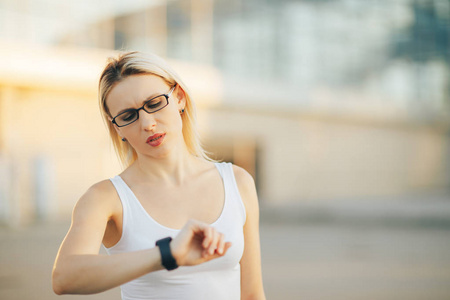 金发碧眼的商业妇女戴着眼镜说话智能手表