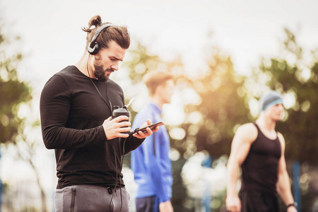 户外跑步锻炼后使用手机和听音乐的体育男子