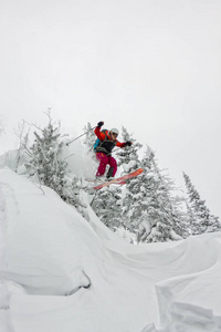 滑雪者 freerider 跳从太阳雪匝道上的山川 森林背景