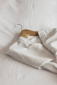 白色床单上的浴衣和木衣架