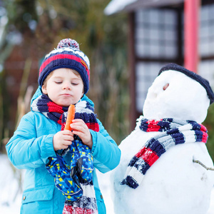 有趣的孩子男孩在冬天的户外堆雪人