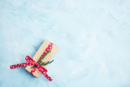 平躺顶部视图圣诞礼品盒包裹在工艺纸与红丝带在淡蓝色背景。新年概念。文本空间