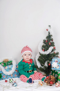穿着圣诞精灵服装的男孩在圣诞树附近的婴儿